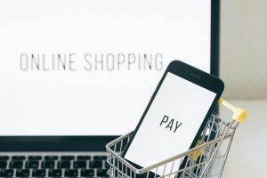 pexels-photo-6214477-6214477 A smartphone in a miniature cart on a laptop symbolizes online shopping and digital payment.